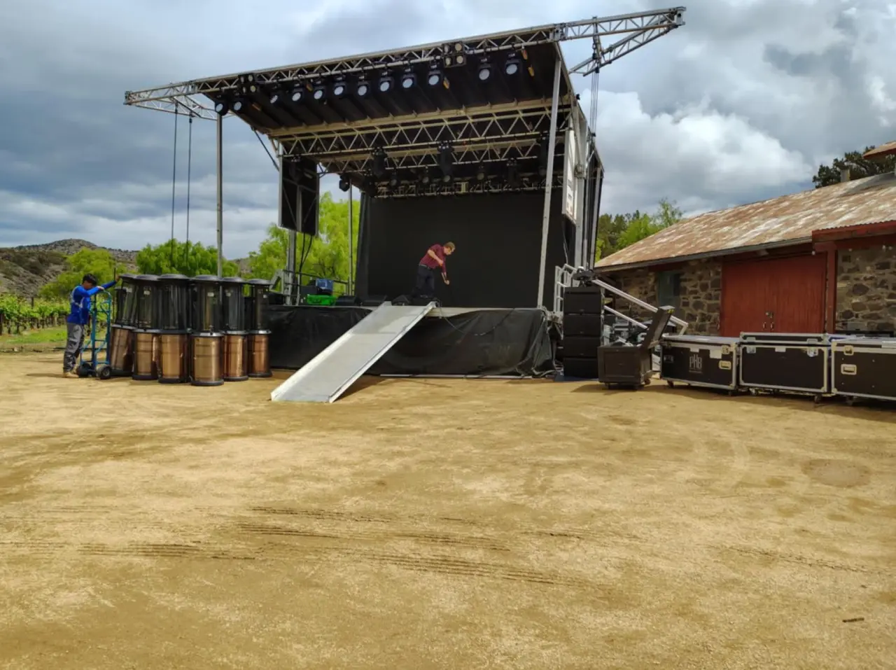 Outdoor stage setup with equipment and barrels.