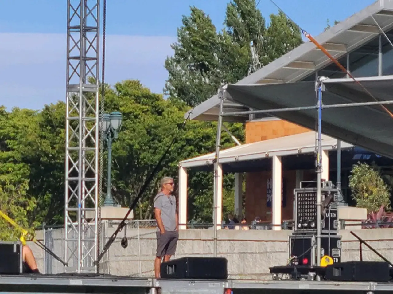 Man standing on outdoor stage, sunny day.