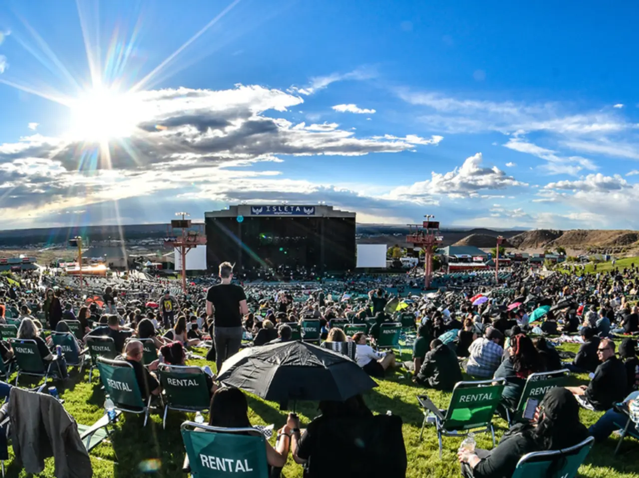 Outdoor concert crowd under sunny sky.