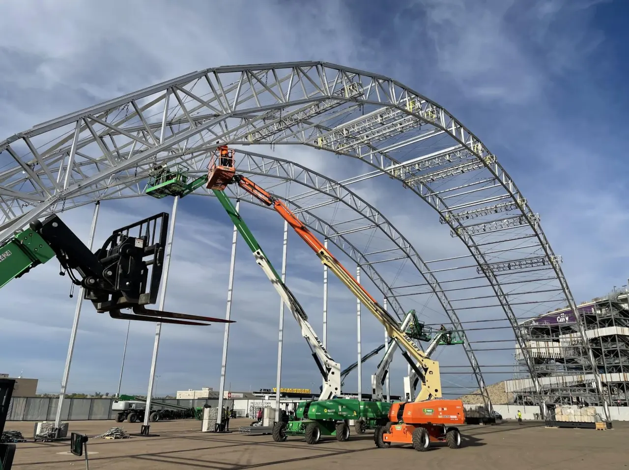 Construction site with cranes and steel framework.