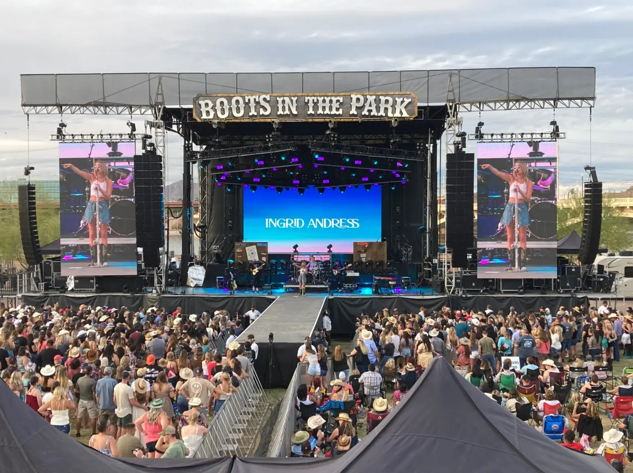 Outdoor concert stage with large crowd gathering.