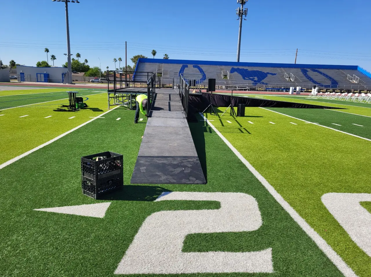 Football field with stage and chairs setup.