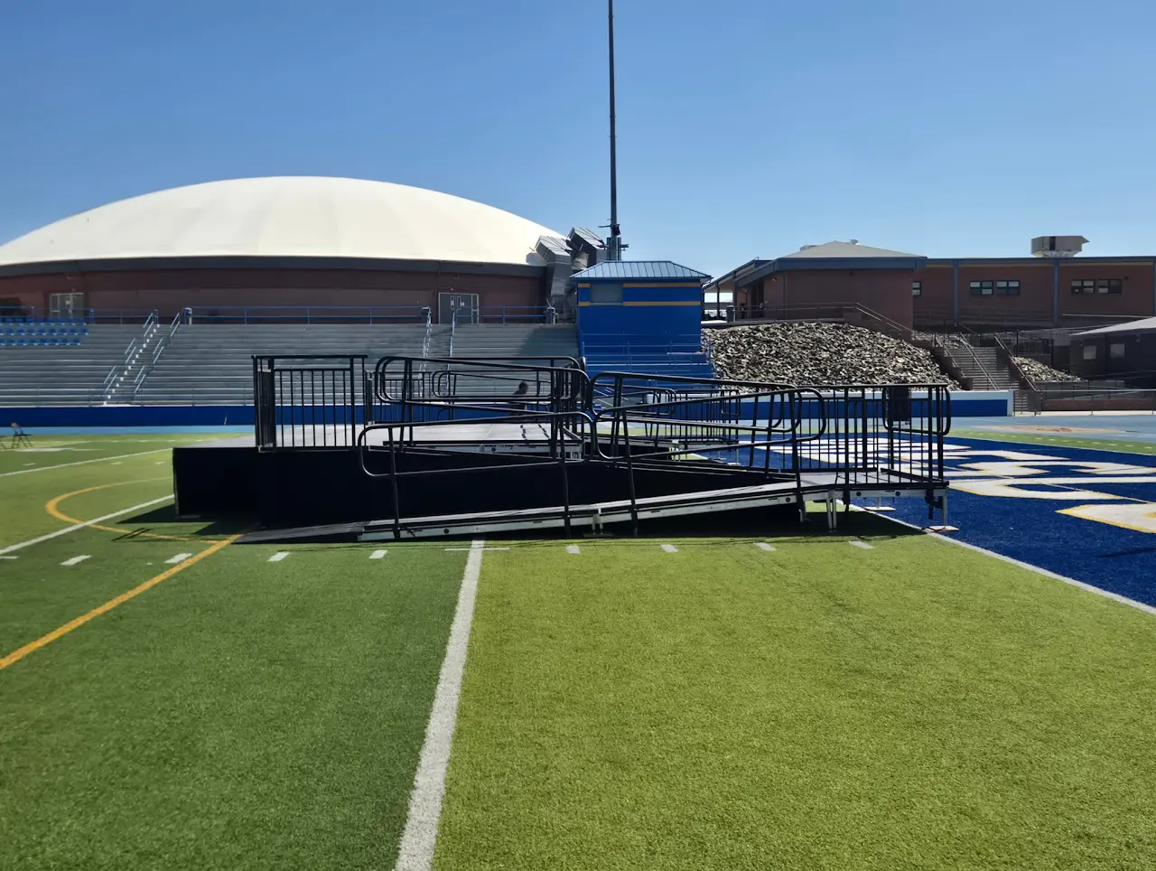 Outdoor sports field with stage and seating.